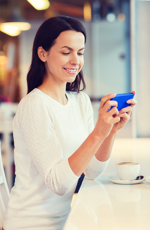 leisure, drinks, people, technology and lifestyle concept - smiling young woman with smartphone drinking coffee at cafe
