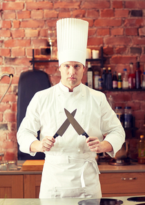 cooking, kitchenware and people concept - happy male chef cook with knife in restaurant kitchen