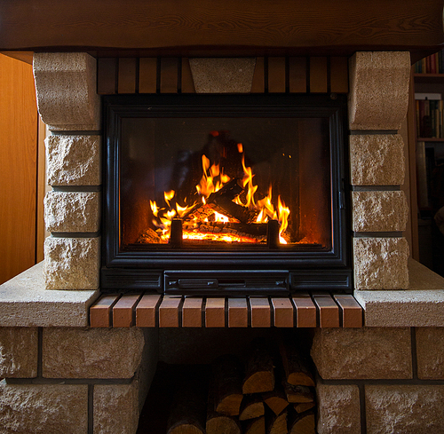 heating, warmth, fire and cosiness concept - close up of burning fireplace at home