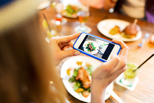 people, leisure, technology and internet addiction concept - close up of woman with smartphone photographing food at restaurant