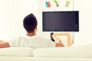 leisure, technology, mass media and people concept - man watching tv and changing channels at home from back