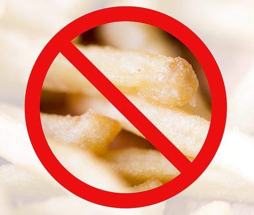 fast food, low carb diet, fattening and unhealthy eating concept - close up of french fries behind no symbol or circle-backslash prohibition sign