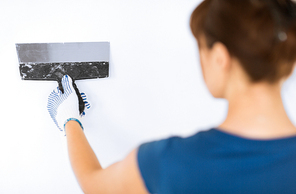 interior design and home renovation concept - woman plastering the wall with trowel