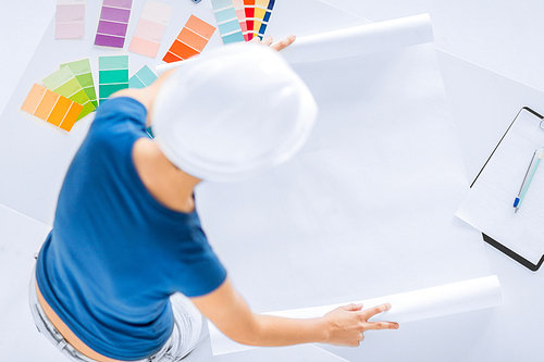 architecture, interior design and renovation concept - woman in helmet working with color samples and blueprint