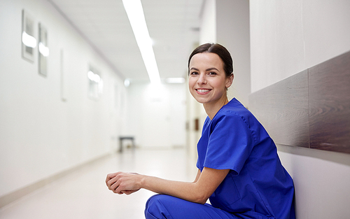 clinic, profession, people, health care and medicine concept - smiling female nurse at hospital corridor