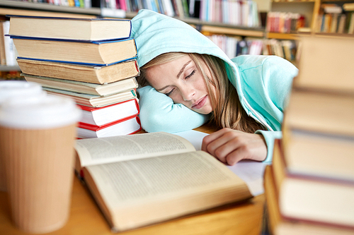 people, education, session, exams and school concept - tired student girl or young woman with books and coffee sleeping in library