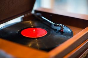 music, technology and object concept - close up of vintage record player with vinyl disc
