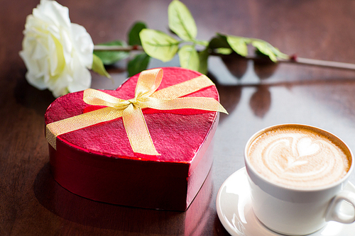 holidays, valentines day, love and drinks concept - close up of gift box, coffee cup and flower on table