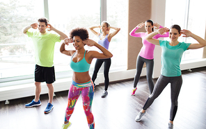 fitness, sport, dance and lifestyle concept - group of smiling people with coach dancing zumba in gym or studio