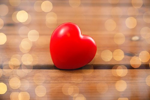 love, romance, valentines day, health care and charity concept - close up of red heart decoration on wood