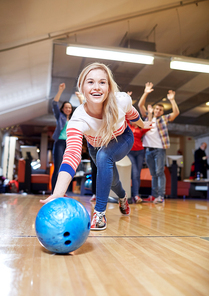 people, leisure, sport and entertainment concept - happy young woman throwing ball in bowling club