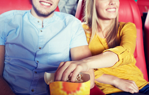 entertainment, leisure and people concept - close up of happy couple watching movie and eating popcorn in theater or cinema