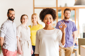 business, startup, people, gesture and teamwork concept - happy young african woman showing ok hand sig over international creative team in office