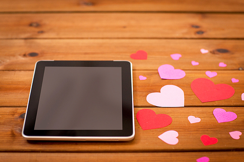 advertisement, romance, valentines day and holidays concept - close up of tablet pc computer and hearts on wood