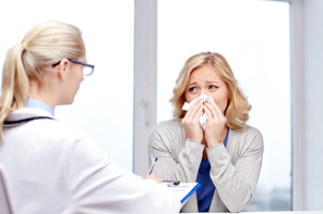 health care, flu, hygiene and people concept - doctor talking to ill woman blowing nose to paper napkin patient at hospital