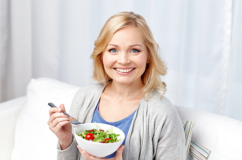 healthy eating, dieting and people concept - smiling young woman eating vegetable salad at home