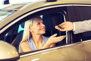 auto business, car sale, consumerism and people concept - happy woman taking car key from dealer in auto show or salon