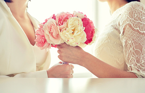 people, homosexuality, same-sex marriage and love concept - close up of happy married lesbian couple with flower bunch