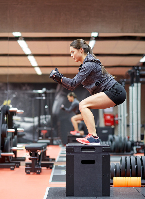 fitness, sport, exercising and people concept - woman doing squats on pnatfom in gym