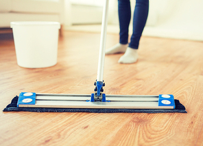 people, housework and housekeeping concept - close up of woman legs with mop cleaning floor at home