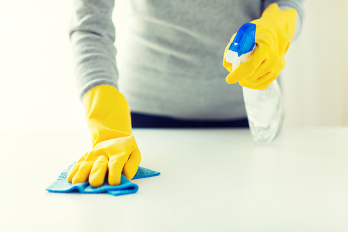 people, housework and housekeeping concept - close up of woman hands cleaning table with cloth and detergent spray at home