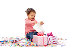 childhood, birthday, party, holidays and people concept - happy smiling little african american baby girl with gift boxes and confetti playing with shopping bag and sitting on floor