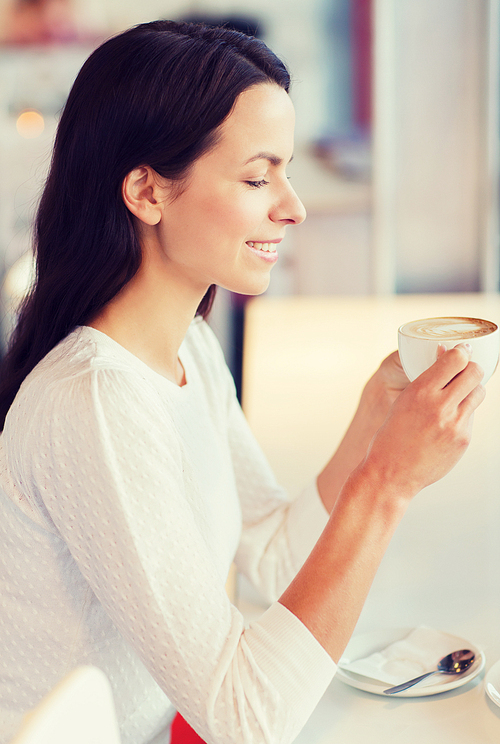 leisure, drinks, people and lifestyle concept - smiling young woman drinking coffee at cafe