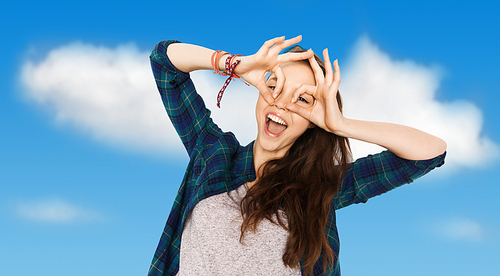 people and teens concept - happy smiling pretty teenage girl making face and having fun over blue sky and clouds background