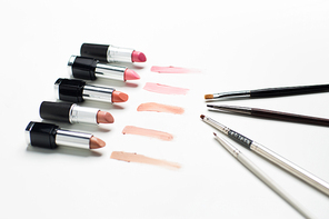 cosmetics, makeup and beauty concept - close up of lipsticks range with brushes