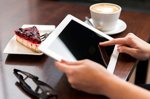 people, business and technology concept - close up of hands with tablet pc computer, eyeglasses, coffee cup and berry cake on table