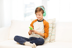 leisure, children, technology and people concept - smiling boy with smartphone and headphones listening to music or playing game at home