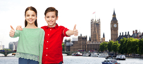 childhood, travel, tourism, gesture and people concept - happy smiling boy and girl hugging and showing thumbs up over london city background