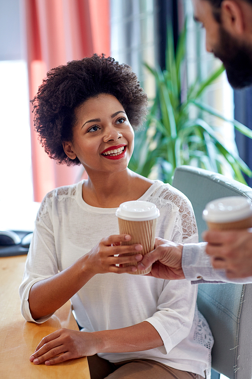 business, startup, people and drinks concept - happy african woman taking coffee cup from man in office