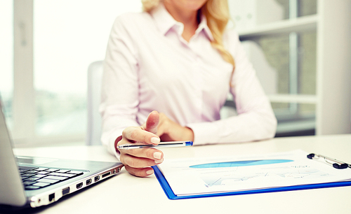 education, business, people and technology concept - close up of smiling businesswoman with laptop computer and papers sitting in office