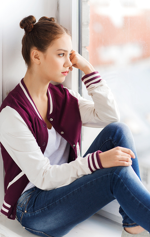 people, emotion and teens concept - sad unhappy pretty teenage girl sitting on windowsill