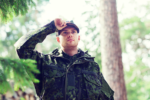 war, army and people concept - young soldier or ranger wearing military uniform in forest