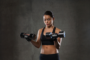fitness, sport, exercising, training and people concept - young woman flexing muscles with dumbbells in gym