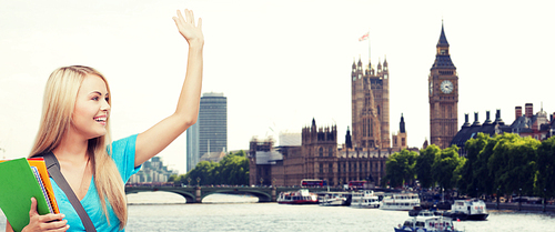 education, school, study abroad, gesture and people concept - smiling student with folders waving hand over london city and thames river background