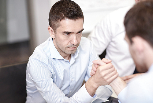 business, people, crisis and confrontation concept - businessmen arm wrestling in office