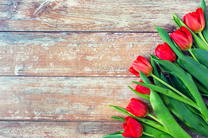 gardening , flowers, advertisement and holidays concept - close up of red tulips on wooden background