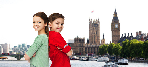 childhood, travel, tourism and people concept - happy smiling boy and girl standing back to back over london city background