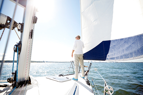 sailing, age, tourism, travel and people concept - senior man on sail boat or yacht floating in sea