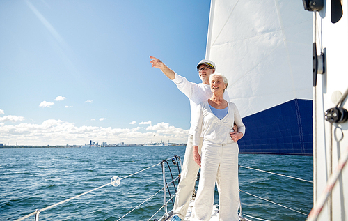 sailing, age, tourism, travel and people concept - happy senior couple pointing finger to something on sail boat or yacht deck floating in sea