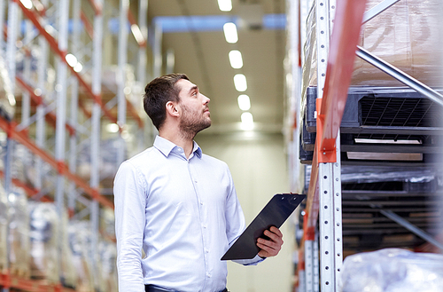 wholesale, logistic, business, export and people concept - happy man or manager with clipboard checking goods at warehouse