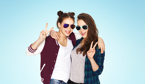 people, friendship, fashion, summer and teens concept - happy smiling pretty teenage girls in sunglasses showing peace hand sign over blue background