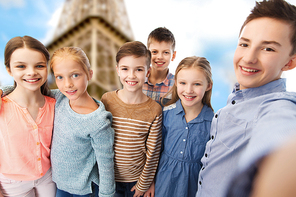 childhood, travel, tourism, technology and people concept - happy children talking selfie over paris eiffel tower background