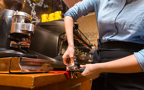 equipment, coffee shop, people and technology concept - close up of woman making coffee by machine at cafe bar or restaurant kitchen