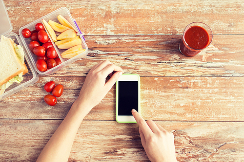 healthy eating, dieting, technology and people concept - close up of woman hands with blank smartphone and food in plastic container on table at home