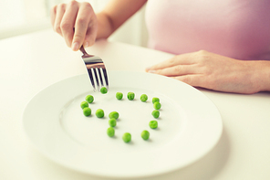 healthy eating, dieting, vegetarian food and people concept - close up of woman with fork eating peas in shape of heart