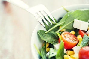 healthy eating, dieting, vegetarian kitchen and cooking concept - close up of vegetable salad bowl and fork at home